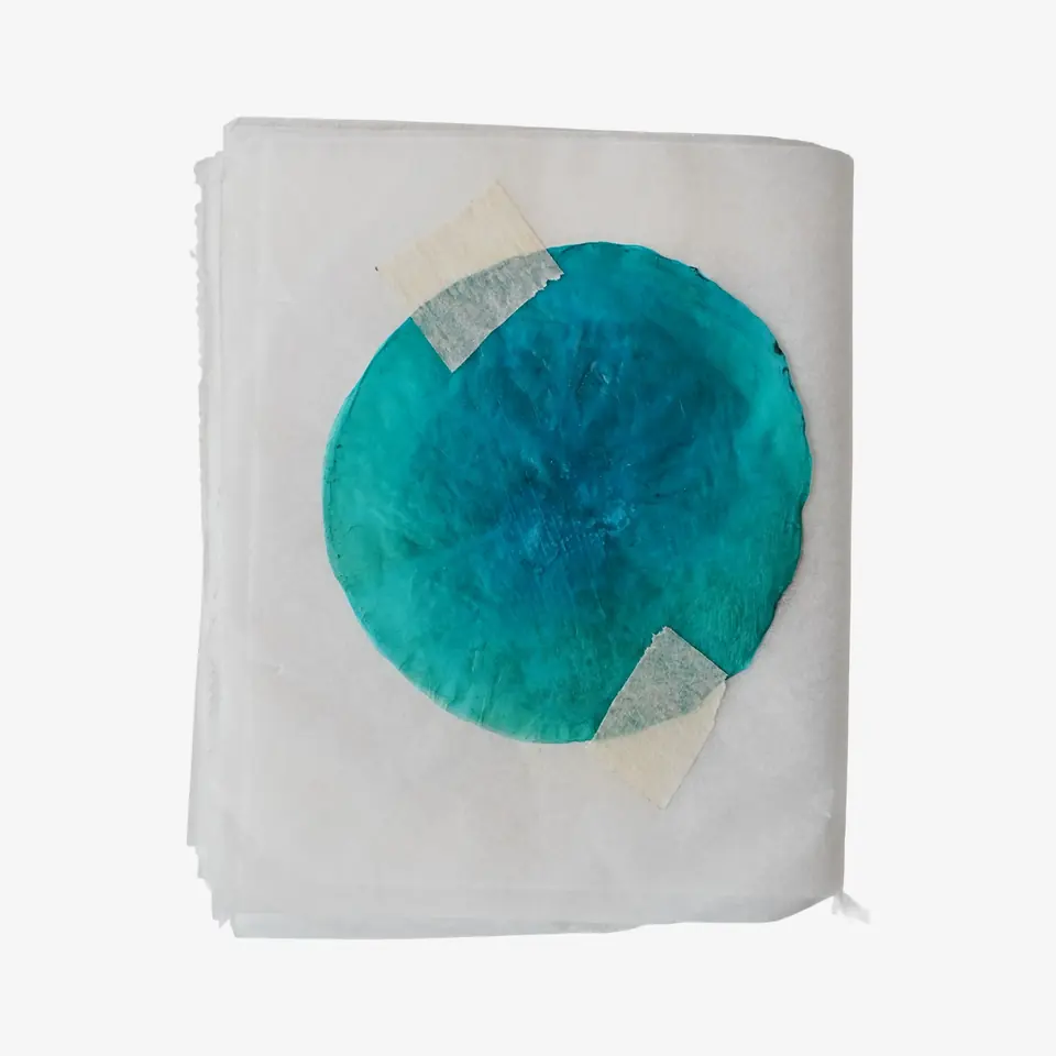 A booklet page with a round teal sheet held down by tape.