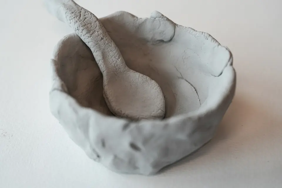 A rough clay bowl with a clay spoon resting in it.