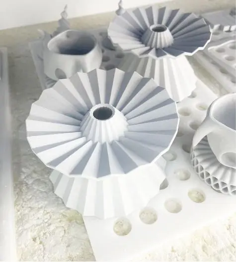 Printed and fired white drippers on a tray, one in front and others behind it.