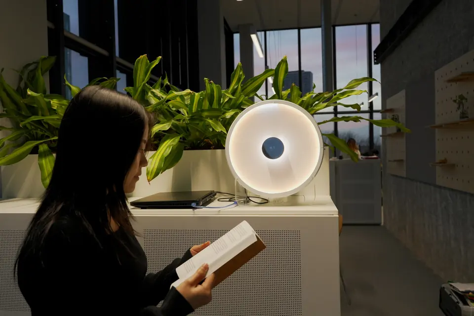 A person reads a book beside the glowing Carecast on a planter cabinet.