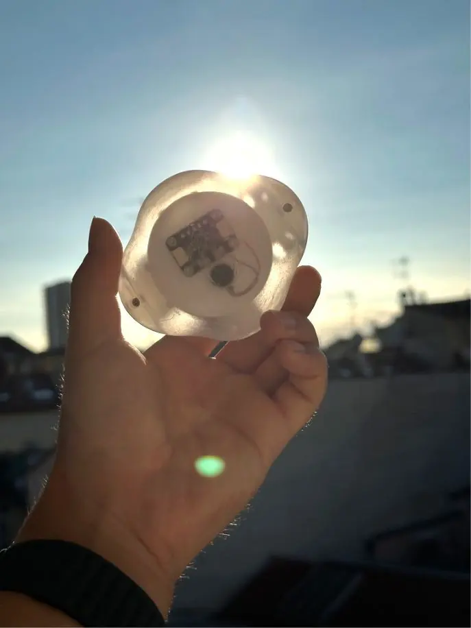 A hand holding up the translucent Terra housing against the low sun.
