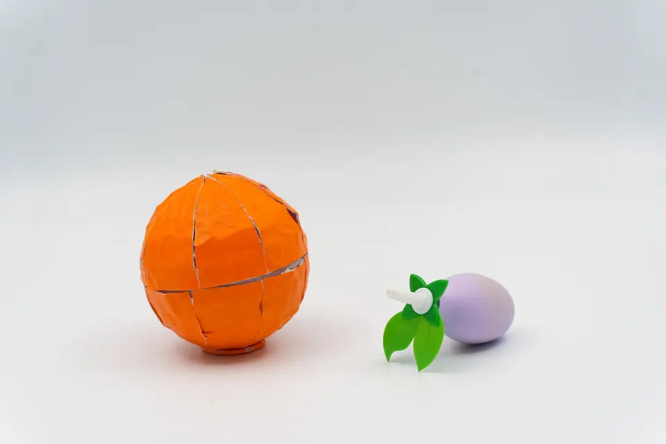 The orange diffuser beside the lavender dropper with green leaves, on a white table.